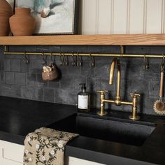 a kitchen with black counter tops and gold faucets on the wall above it