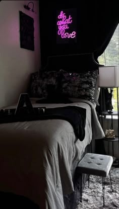 a bed room with a neatly made bed and a neon sign