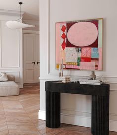 a painting on the wall next to a black console table in a white living room