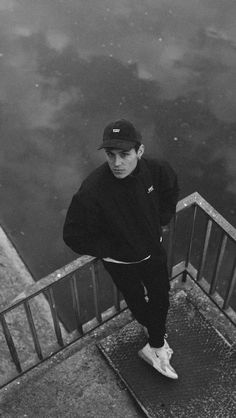 a young man standing on the edge of a railing next to a body of water