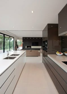 a modern kitchen with white counter tops and brown cabinetry, along with large windows