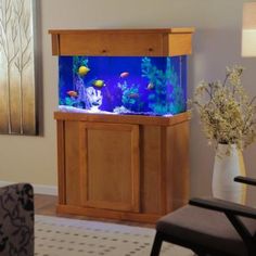 a fish tank sitting on top of a wooden cabinet in a living room next to a chair