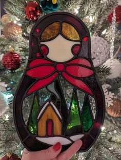 a stained glass christmas ornament with a woman holding a house