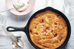 a skillet with a cake in it next to some spoons and cups on a table