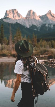 a person with a hat and backpack walking by water