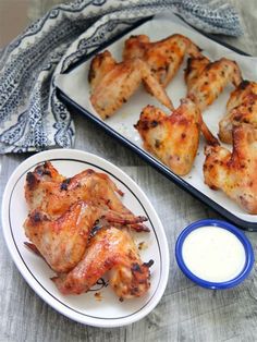 chicken wings and ranch dressing on a white plate next to a blue and white dish