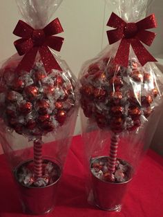 two plastic buckets filled with candy and wrapped in cellophane, sitting on a red table cloth