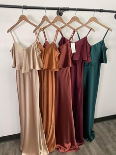 four dresses hanging on a rack in front of a wall