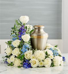 a vase and flowers on a marble table with blue and white flowers in the center