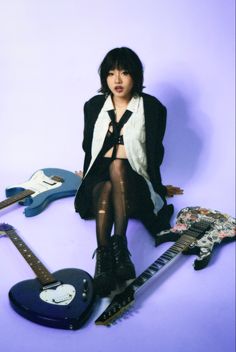 a woman sitting on the ground next to some guitars and guitar strings in front of her