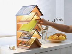 a person placing books on top of a house shaped book stand