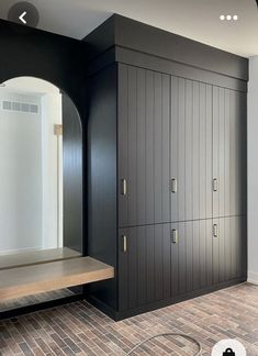 an empty room with black cabinets and wood flooring in the center, along with a wooden bench