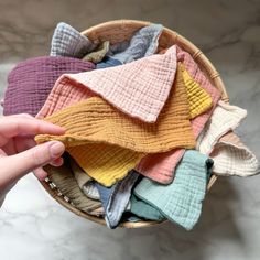 a basket filled with lots of different colored cloths on top of a marble counter