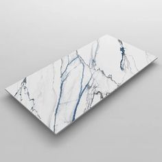 a white and blue marble cutting board sitting on top of a gray surface with an abstract design