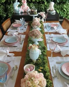 the table is set for easter dinner with bunny decorations and flowers in vases on each side