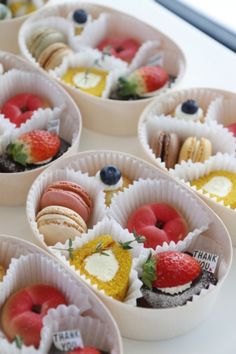 small trays filled with different types of pastries on a white counter top,