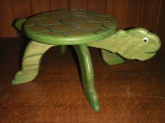 a green turtle stool sitting on top of a wooden table