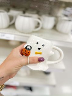 a hand holding a coffee mug with a face painted on it and a pumpkin in the middle