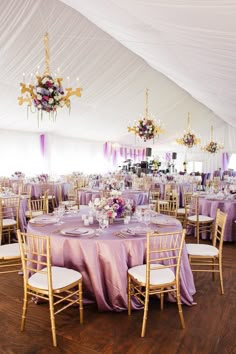 the inside of a tent with tables, chairs and chandeliers set up for an event