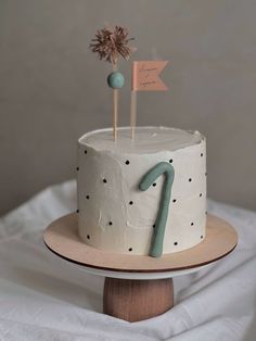 a white cake with blue icing and a star on top, sitting on a wooden stand