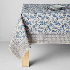 a blue and white table cloth with flowers on it, sitting on top of a wooden stand