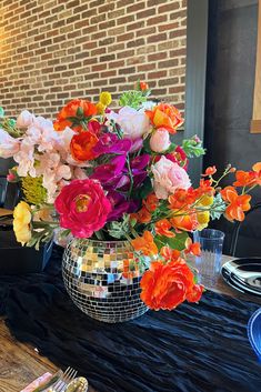 a vase filled with lots of colorful flowers on top of a black cloth covered table