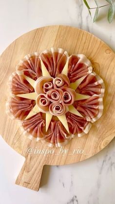 a wooden cutting board topped with sliced ham and cheese on top of a marble counter