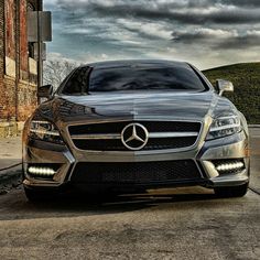 the front end of a silver mercedes cla parked in front of an old brick building