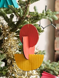 an ornament hanging from a christmas tree decorated with red, yellow and blue paper