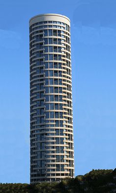 a very tall building sitting on the side of a hill next to a tree covered hillside