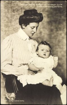 an old black and white photo of a woman holding a baby in her lap,