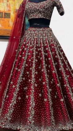 a red and gold bridal gown on display in front of a large piece of art