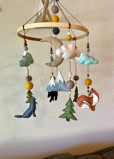 a wind chime with various animals hanging from it's sides and trees on the other side