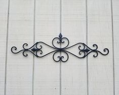 a metal wall hanging on the side of a building with an iron scrolled design