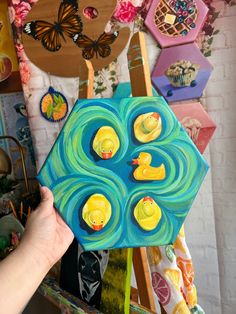 a person holding up a piece of art with rubber ducks on it