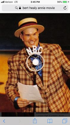 a man in a plaid jacket and hat holding a paper