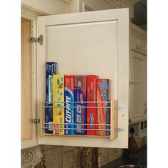 the kitchen cabinet door is open and has several cans on it, as well as an over - the - sink spice rack