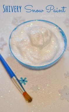 a blue and white bowl with snow paint next to a brush on top of it