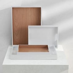 two white boxes sitting on top of a table next to each other with wood in them