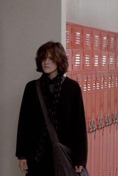 a person standing in front of a wall with red lockers