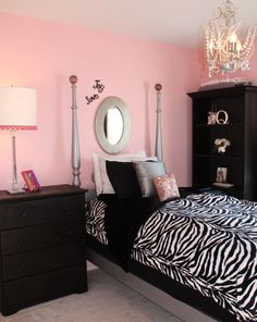 a bedroom decorated in pink and black with zebra print bedding, chandelier