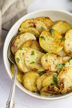 a white bowl filled with cooked potatoes and garnished with parsley