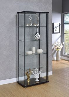 a glass display case with candles and ornaments on it's sides in a living room