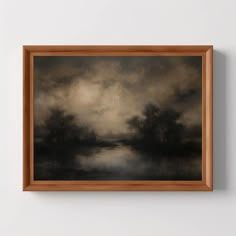 a painting hanging on the wall next to a wooden framed artwork piece with an image of trees and water in it