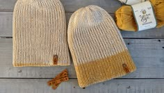 two yellow knitted mitts next to some yarn on a wooden table with a crochet hook