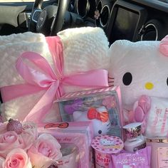 a hello kitty stuffed animal sitting in the back seat of a car filled with baby items