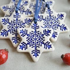 a snowflake ornament hanging from a blue ribbon on a white table