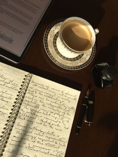 a cup of coffee next to an open notebook