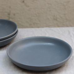 two gray plates sitting on top of a white cloth