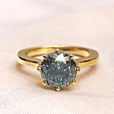 a close up of a diamond ring on a white cloth with gold trimmings